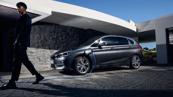Tročetvrtinski bočni prikaz plug-in hibrida BMW-a 225xe Active Tourer ispred zgrade Tročetvrtinski bočni prikaz plug-in hibrida BMW-a 225xe Active Tourer ispred zgrade s modelom