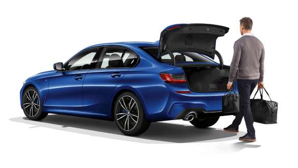 BMW serije 3 Limuzina, automatsko otvaranje prtljažnika. Tročetvrtinski stražnji prikaz BMW-a serije 3 Limuzina s vozačem koji automatski otvara vrata prtljažnika nogom.