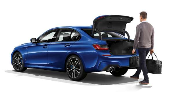 BMW serije 3 Limuzina (G20), automatsko otvaranje vrata prtljažnika. Tročetvrtinski stražnji prikaz u mirovanju BMW serije 3 Limuzina (G20) s vozačem koji automatski otvara vrata prtljažnika s nogom.