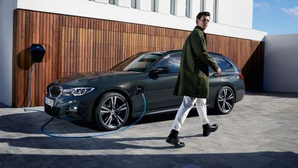 Tročetvrtinski bočni prikaz plug-in hibrida BMW-a serije 3 Touring 2021 G21 priključen na BMW Wallbox uređaj Tročetvrtinski bočni prikaz plug-in hibrida BMW-a serije 3 Touring 2021 G21 priključen na BMW Wallbox uređaj s modelom