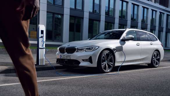 Tročetvrtinski prikaz prednjeg kraja plug-in hibrida BMW-a serije 3 Touring 2021 G21 prilikom napajanja Tročetvrtinski prikaz prednjeg kraja plug-in hibrida BMW-a serije 3 Touring 2021 G21 prilikom napajanja ispred zgrade