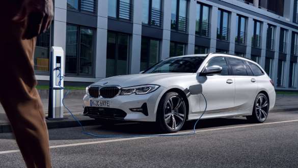 Plug-in hibrid BMW serije 3 Touring 2021 G21 tročetvrtinski pogled sprijeda punjenje Plug-in hibrid BMW serije 3 Touring 2021 G21 tročetvrtinski pogled sprijeda punjenje ispred zgrade