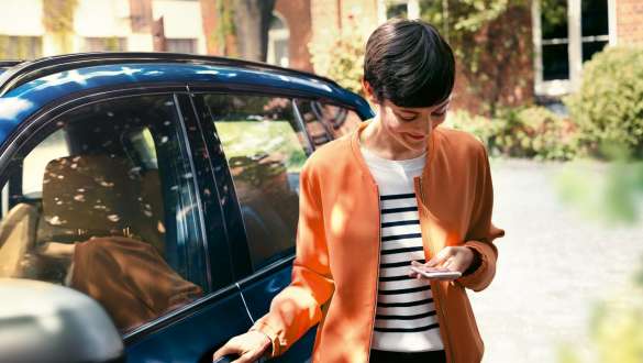 Žena gleda na pametni telefon BMW serije 5 Touring G31 Žena izlazi iz BMW-a gledajući na pametni telefon BMW serije 5 Touring G31 Facelift 2020
