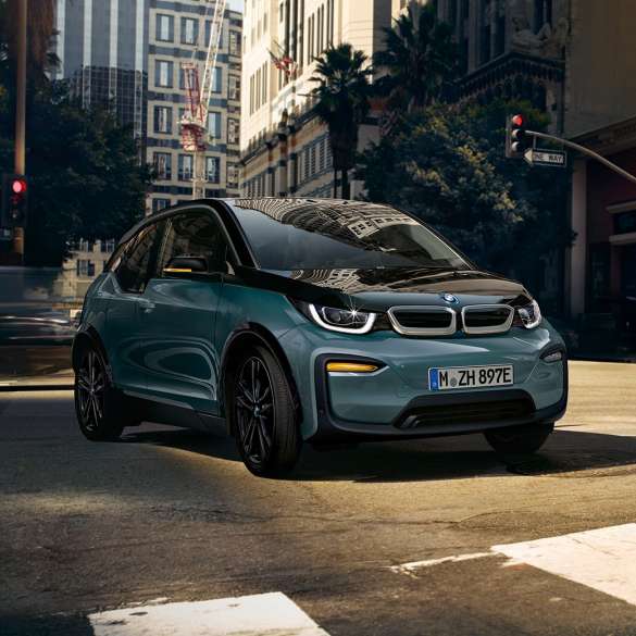 Tročetvrtinski prikaz prednjeg kraja BMW-a i3 2018 u vožnji Tročetvrtinski prikaz prednjeg kraja BMW-a i3 I01 2018 Jucaro bež boje s Frozen Grey metalik detaljima u vožnji u urbanom okruženju