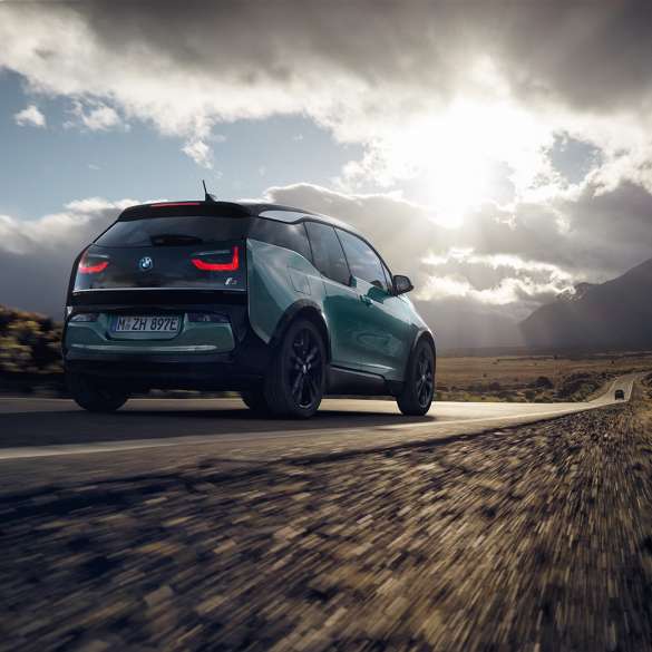 Tročetvrtinski prikaz stražnjeg kraja BMW-a i3 2018 u vožnji autocestom Tročetvrtinski prikaz stražnjeg kraja BMW-a i3 I01 2018 Jucaro bež boje s Frozen Grey metalik detaljima u vožnji autocestom