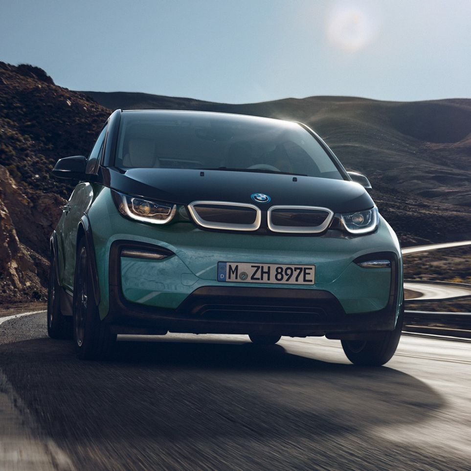 Bočni prikaz BMW-a i3 2018 u vožnji Bočni prikaz BMW-a i3 I01 2018 Jucaro bež boje s Frozen Grey metalik detaljima u vožnji u urbanom okruženju
