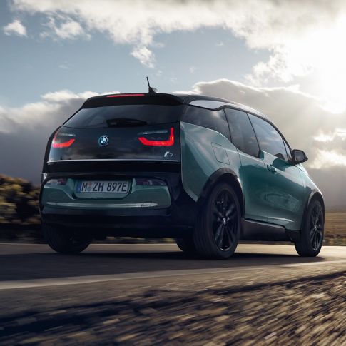Tročetvrtinski prikaz stražnjeg kraja BMW-a i3 2018 u vožnji na autocesti Tročetvrtinski prikaz stražnjeg kraja BMW-a i3 I01 2018 Jucaro bež boje s Frozen Grey metalik detaljima u vožnji na autocesti