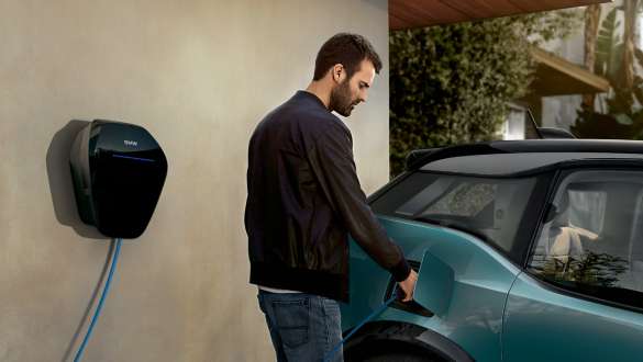 Čovjek napaja svoj BMW i3 2018 na BMW Wallbox uređaju Čovjek s BMW Wallbox kablovima za napajanje ispred BMW-a i3 I01 2018 Jucaro bež boje s Frozen Grey metalik detaljima