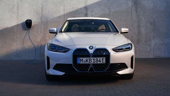 Pogled sprijeda BMW Wallbox BMW i4 eDrive40 G26 2021 BMW i4 eDrive40 G26 2021 Mineral White pogled sprijeda ispred kuće sa BMW Wallbox stanicom za punjenje