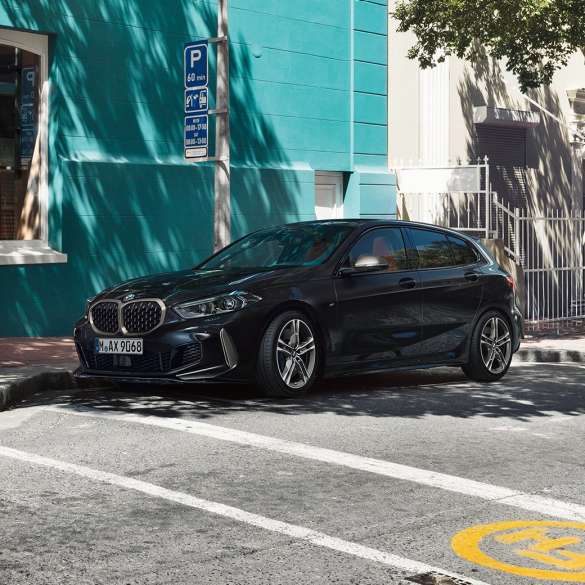 BMW M135i xDrive, tročetvrtinksi bočni prikaz. Potpuno novi BMW M135i xDrive u Black Sapphire metalik boji, tročetvrtinksi bočni prikaz prilikom parkiranja.