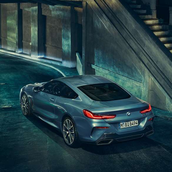 BMW M850i xDrive Coupé, tročetvrtinski stražnji lijevi pogled. BMW M850i xDrive Coupé u Barcelona Blue metalik, tročetvrtinski stražnji lijevi pogled, u mirovanju po noći.