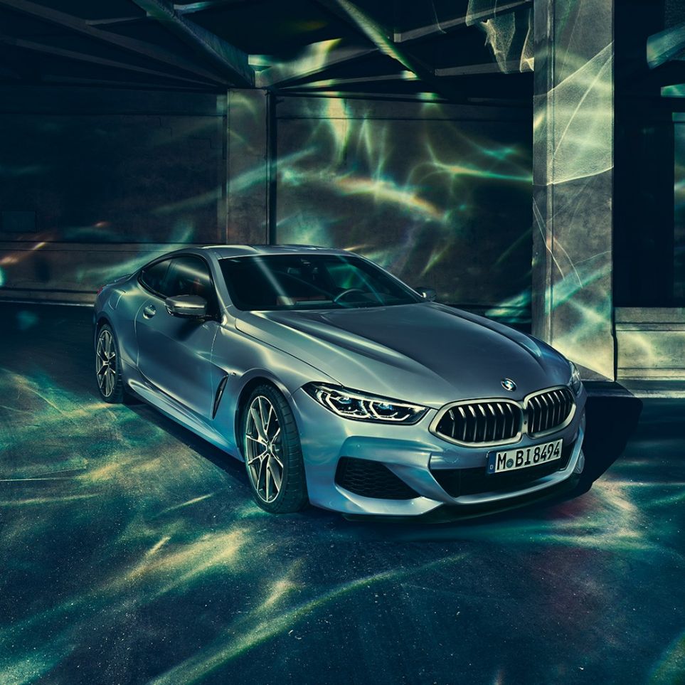BMW M850i xDrive Coupé, tročetvrtinski prednji lijevi pogled. BMW M850i xDrive Coupé u Barcelona Blue metalik, tročetvrtinski prednji lijevi pogled, u mirovanju ispred građevine.