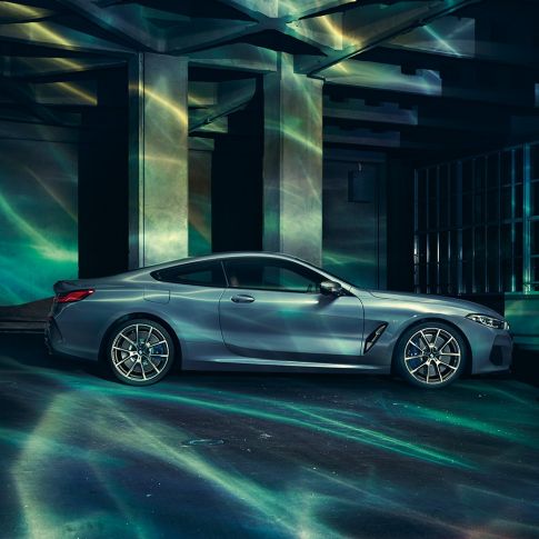 BMW M850i xDrive Coupé, bočni pogled. BMW M850i xDrive Coupé u Barcelona Blue metalik, bočni pogled, u mirovanju ispred građevine.
