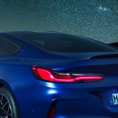 M stražnji spojler BMW M8 Competition Coupé u Marina Bay Blue metalik, krupni plan po noći bočnog dijela sa M stražnjim spojlerom u karbonu.