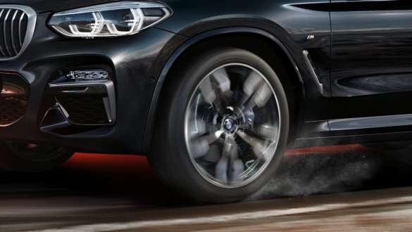 BMW X3 M40i i BMW X3 M40d, bočni prikaz. BMW X3 M40i i BMW X3 M40d u Black Sapphire metalik boji, u vožnji, vanjština, bočni prikaz s rotirajućim lakometalnim kotačem.