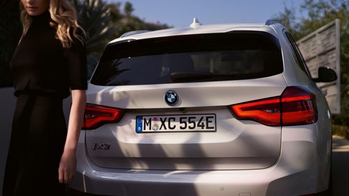 Stražnji dio s BMW i specifičnim difuzorom BMW iX3 G08 stražnji prikaz sa ženom Stražnji dio s BMW i sprecifičnim difuzorom BMW iX3 G08 2020 Mineral White metalik stražnji prikaz sa ženom