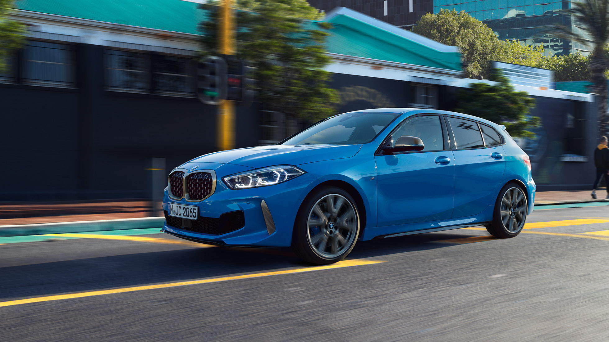 BMW serije 1, tročetvrtinski bočni prikaz. BMW serije 1 u Misano Blue metalik boji, tročetvrtinski prikaz prednjeg kraja prilikom vožnje.