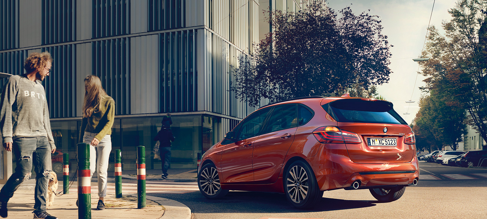 Tročetvrtinski prikaz stražnjeg kraja BMW-a serije 2 Active Tourer 220i Tročetvrtinski prikaz stražnjeg kraja BMW-a serije 2 Active Tourer 220i F45 Facelift 2018 Sunset Orange metalik boje u vožnji na cesti