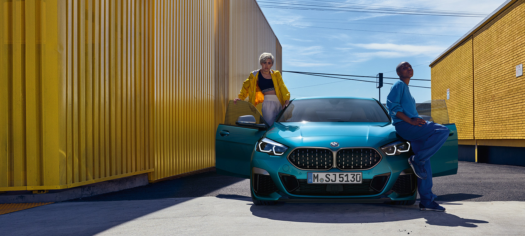 BMW serije 2 Gran Coupé F44, pogled sprijeda BMW serije 2 Gran Coupé F44 Snapper Rocks Blue, pogled sprijeda sa otvorenim vratima i dvoje ljudi u vozilu