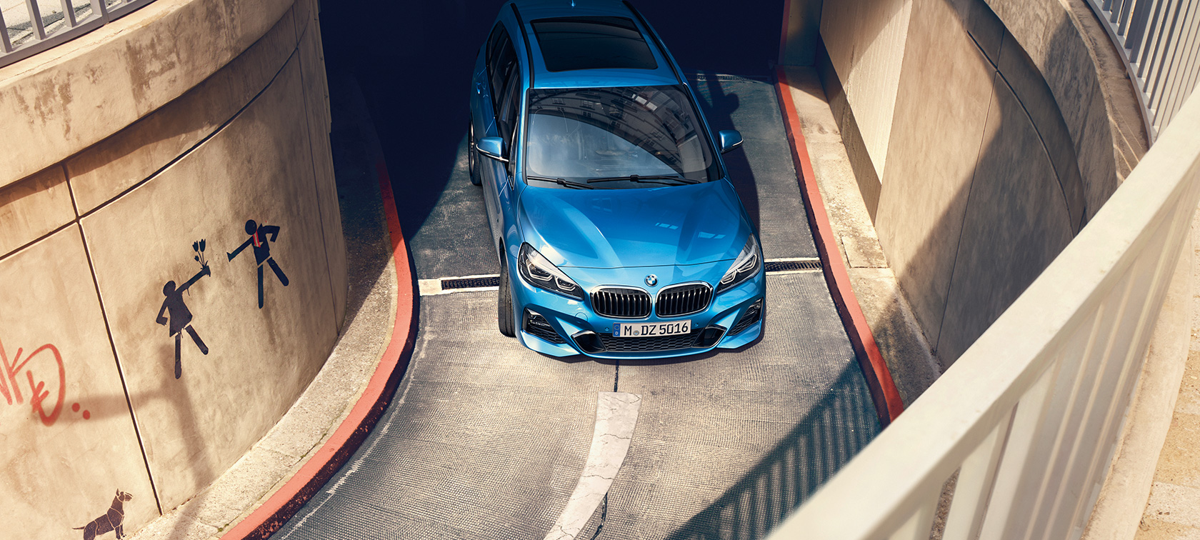 BMW-a serije 2 Gran Tourer u vožnji višekatnim parkiralištem Prikaz iz ptičje perspective BMW-a serije 2 Gran Tourer F46 Estoril Blue metalik boje u vožnji višekatnim parkiralištem