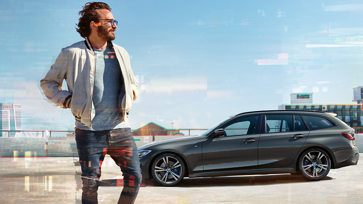 BMW serije 3 Touring (G21), tročetvrtinski pogled sprijeda dizajn BMW serije 3 Touring, (G21), dravite grey, tročetvrtinski pogled sprijeda u vožnji mostom ispred ruralne pozadine