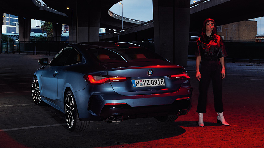 BMW serije 4 Coupé (G22), Artic Race Blue metalik, stražnji pogled sa osobom BMW serije 4 Coupé (G22), Artic Race Blue metalik, stražnji pogled sa osobom