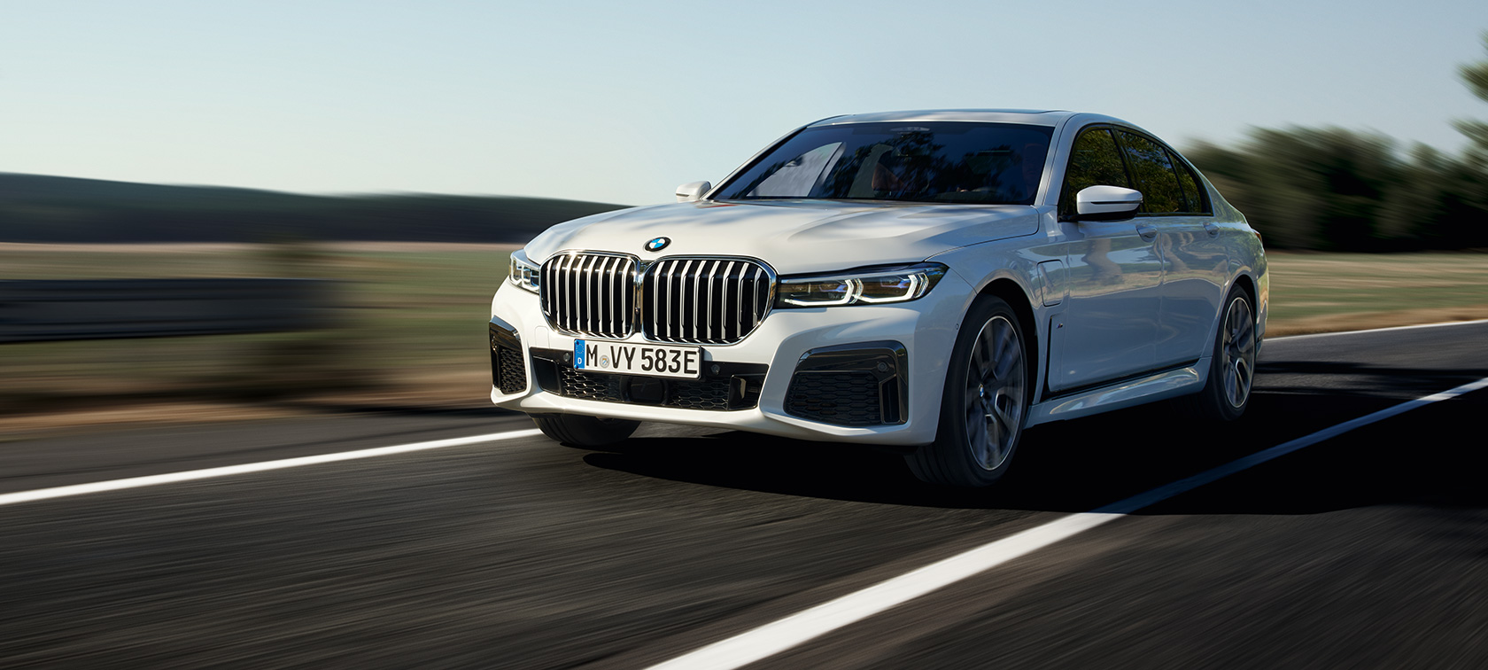 BMW 745e limuzina plug-in hybrid G11 G12 Mineral White metalik tročetvrtinski pogled BMW 745e limuzina plug-in hybrid G11 G12 Mineral White metalik tročetvrtinski pogled sprijeda u vožnji na cesti