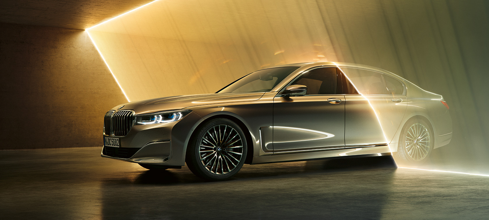 BMW serije 7 limuzina G11 G12 2019 Bernina Grey Amber Effect tročetvrtinski pogled sprijeda okružen sa zrakama svjetlosti