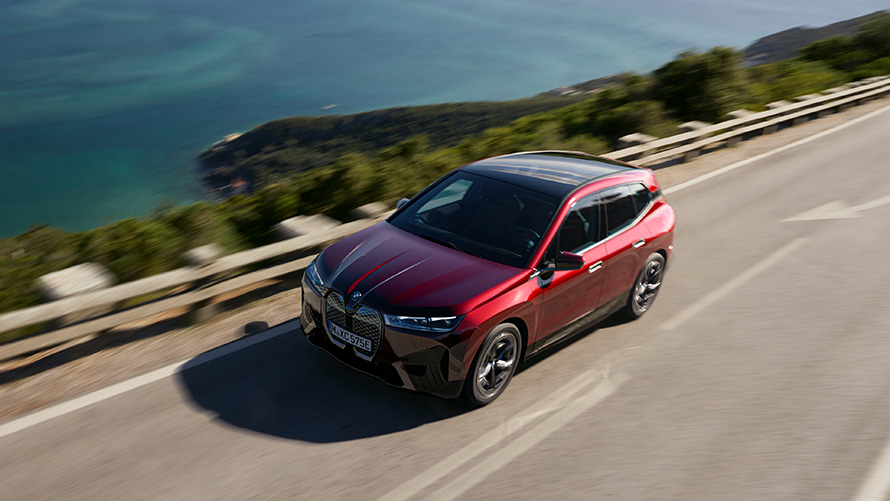 BMW iX i20 električni SUV; Doseg BMW-a iX xDrive50 BMW iX i20 2021 električni SUV; BMW iX xDrive50 Aventurin Red boje na cesti
