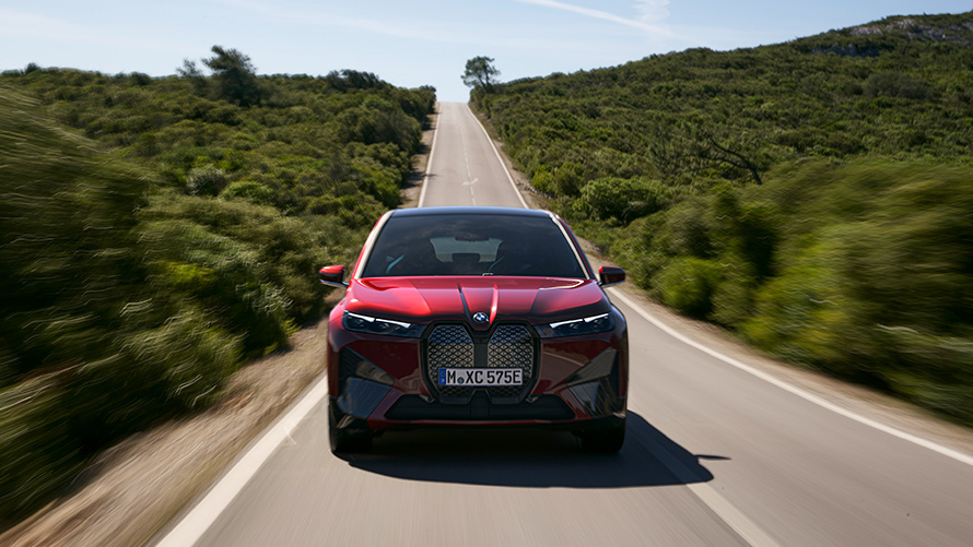 BMW iX i20 električni SUV; Doseg BMW-a iX xDrive50 BMW iX i20 2021 električni SUV; BMW iX xDrive50 Aventurin Red boje na cesti