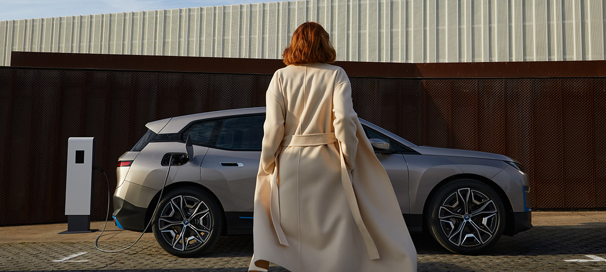 BMW iX bočni pogled u mirovanju BMW iX Cashmere Silver i20 bočni pogled u mirovanju sa modelom u prvom planu