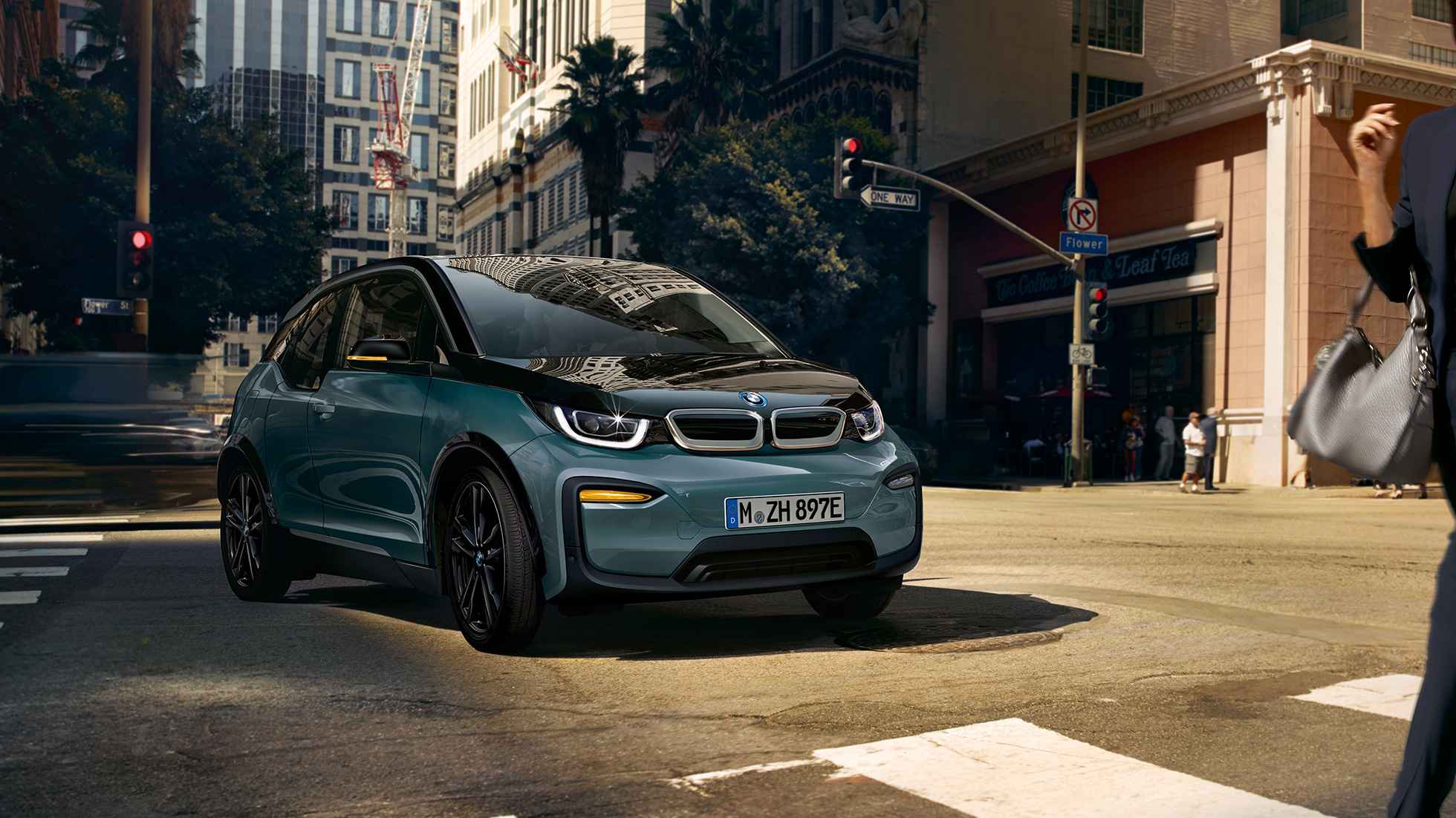Tročetvrtinski prikaz prednjeg kraja BMW-a i3 2018 u vožnji Tročetvrtinski prikaz prednjeg kraja BMW-a i3 I01 2018 Jucaro bež boje s Frozen Grey metalik detaljima u vožnji u urbanom okruženju