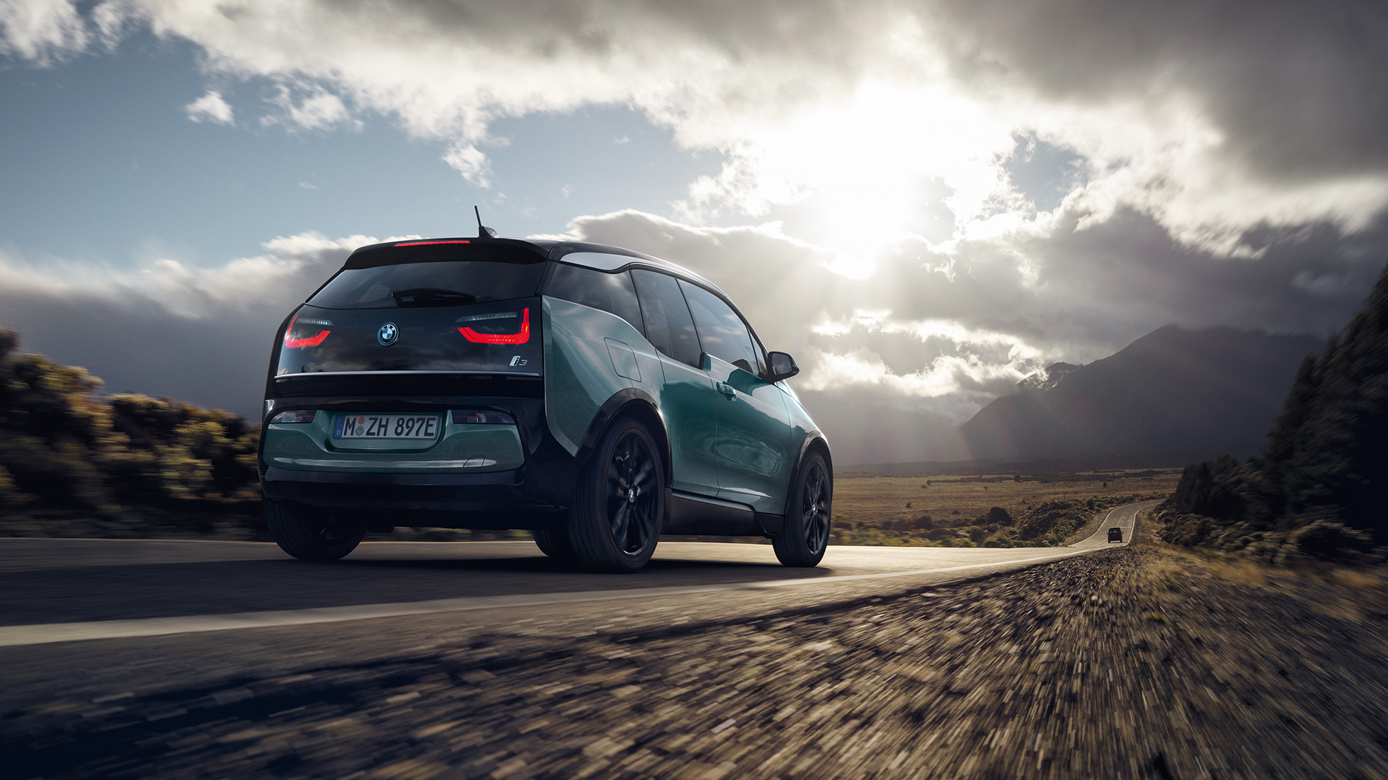 Tročetvrtinski prikaz stražnjeg kraja BMW-a i3 2018 u vožnji na autocesti Tročetvrtinski prikaz stražnjeg kraja BMW-a i3 I01 2018 Jucaro bež boje s Frozen Grey metalik detaljima u vožnji na autocesti