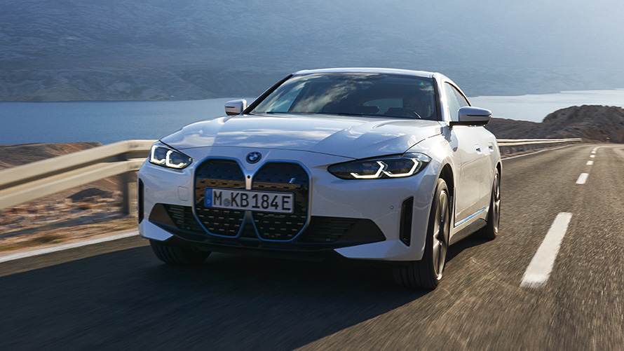 Tročetvrtinski pogled sprijeda BMW i4 eDrive40 G26 2021 u vožnji BMW i4 eDrive40 G26 2021 Mineral White tročetvrtinski pogled sprijeda u vožnji