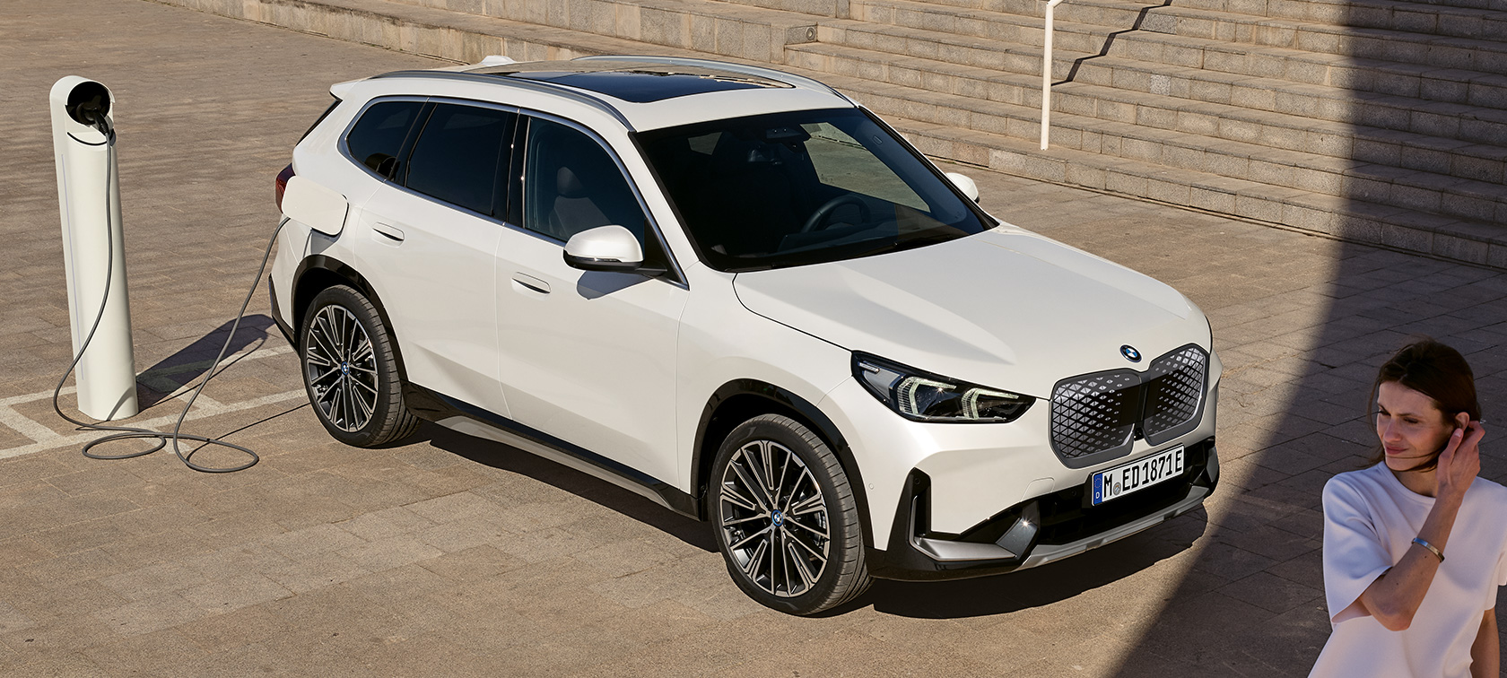 BMW iX1 U11 BEV bočni pogled punjenje BMW iX1 U11 BEV 2022 Mineral White metalik dvotrećinski bočni pogled kod punjenja