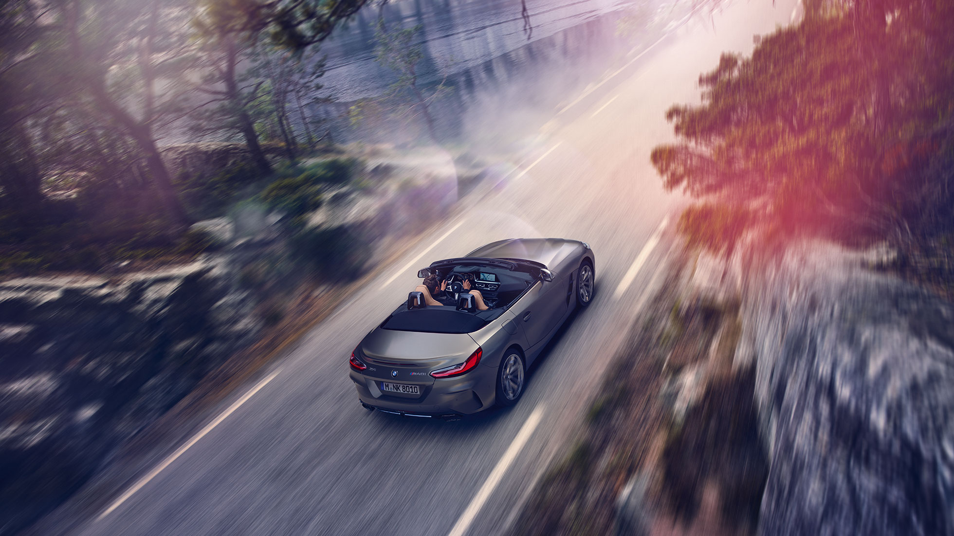BMW Z4 M40i G29 Cabrio sa spuštenim krovom BMW Z4 M40i Roadster G29 2019 Cabrio BMW Individual Frozen Grey metalik boje u vožnji sa spuštenim krovom iz ptičje perspektive.