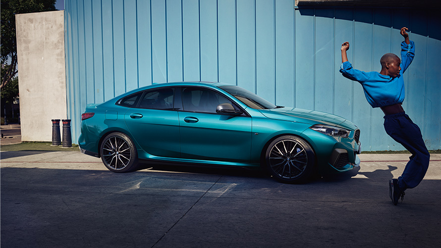 BMW M235i xDrive Gran Coupé F44 pogled s boka sa ženom u prvom planu BMW M235i xDrive Gran Coupé F44 Snapper Rocks Blue metalik pogled s boka sa ženom u prvom planu