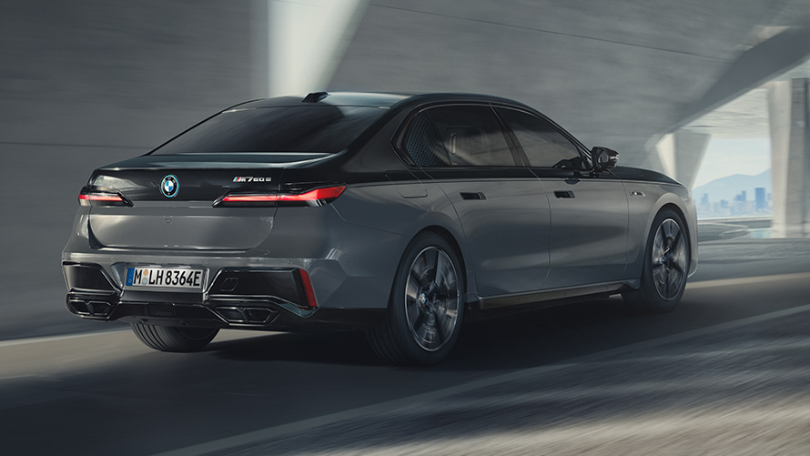 BMW M760e xDrive Limuzina G70 M Performance paket BMW M760e xDrive Limuzina G70 M Performance paket BMW Individual dvotonska Black Sapphire metalik boja BMW Individual Dravite Grey metalik tročetvrtinski stražnji pogled u vožnji na ulici