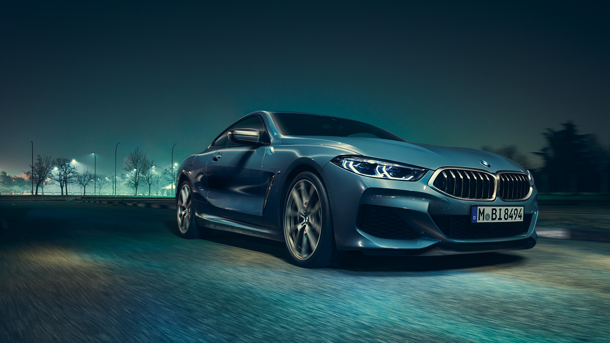 BMW M850i xDrive Coupé, tročetvrtinski prednji lijevi pogled. BMW M850i xDrive Coupé u Barcelona Blue metalik, tročetvrtinski prednji lijevi pogled, vožnja noću.