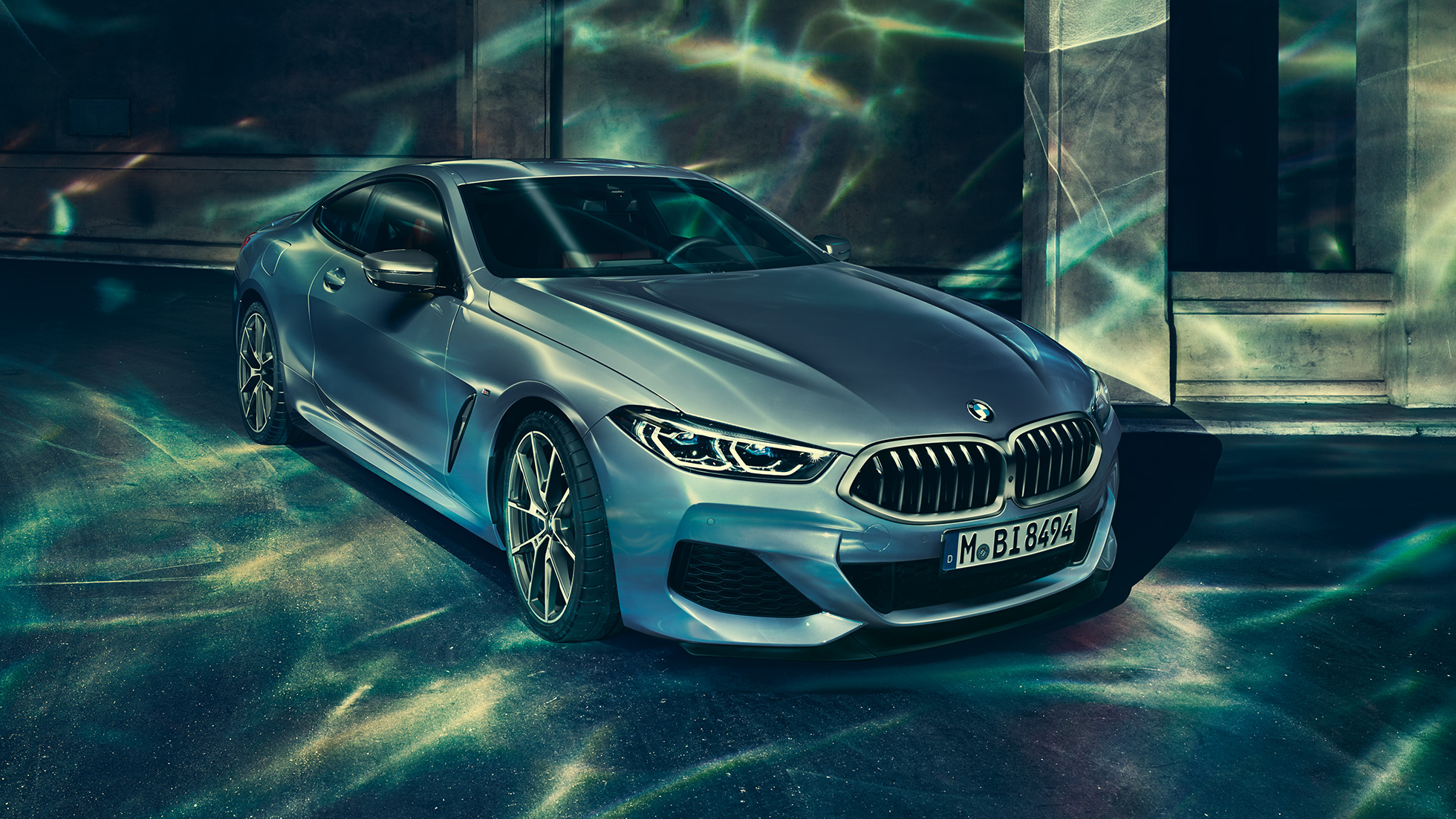 BMW M850i xDrive Coupé, tročetvrtinski prednji lijevi pogled. BMW M850i xDrive Coupé u Barcelona Blue metalik, tročetvrtinski prednji lijevi pogled, u mirovanju ispred građevine.