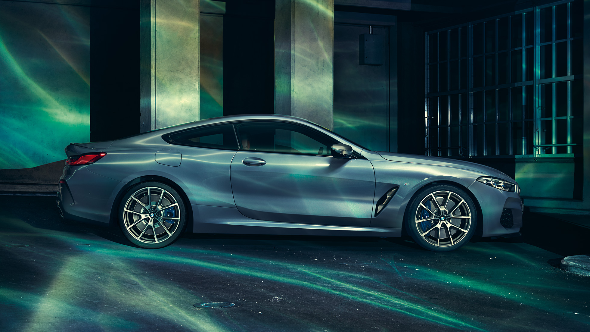 BMW M850i xDrive Coupé, bočni pogled. BMW M850i xDrive Coupé u Barcelona Blue metalik, bočni pogled, u mirovanju ispred građevine.