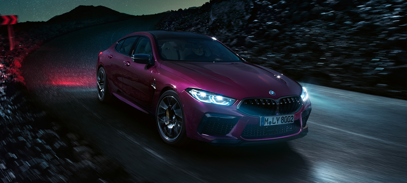 Tročetvrtinski prikaz prednjeg kraja BMW-a M8 Competition Gran Coupé Tročetvrtinski prikaz prednjeg kraja BMW-a M8 Competition Gran Coupé F93 BMW Individual Ametrine metalik boje noću u vožnji