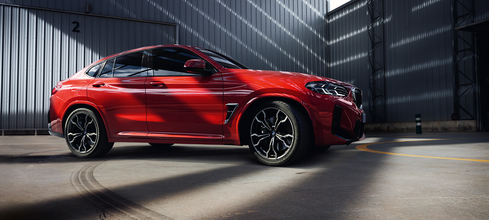 Tročetvrtinski pogled sprijeda BMW X4 M F98 LCI Facelift 2021 BMW X4 M F98 LCI Facelift 2021 Toronto Red metalik tročetvrtinski pogled sprijeda unutar industrijske zgrade