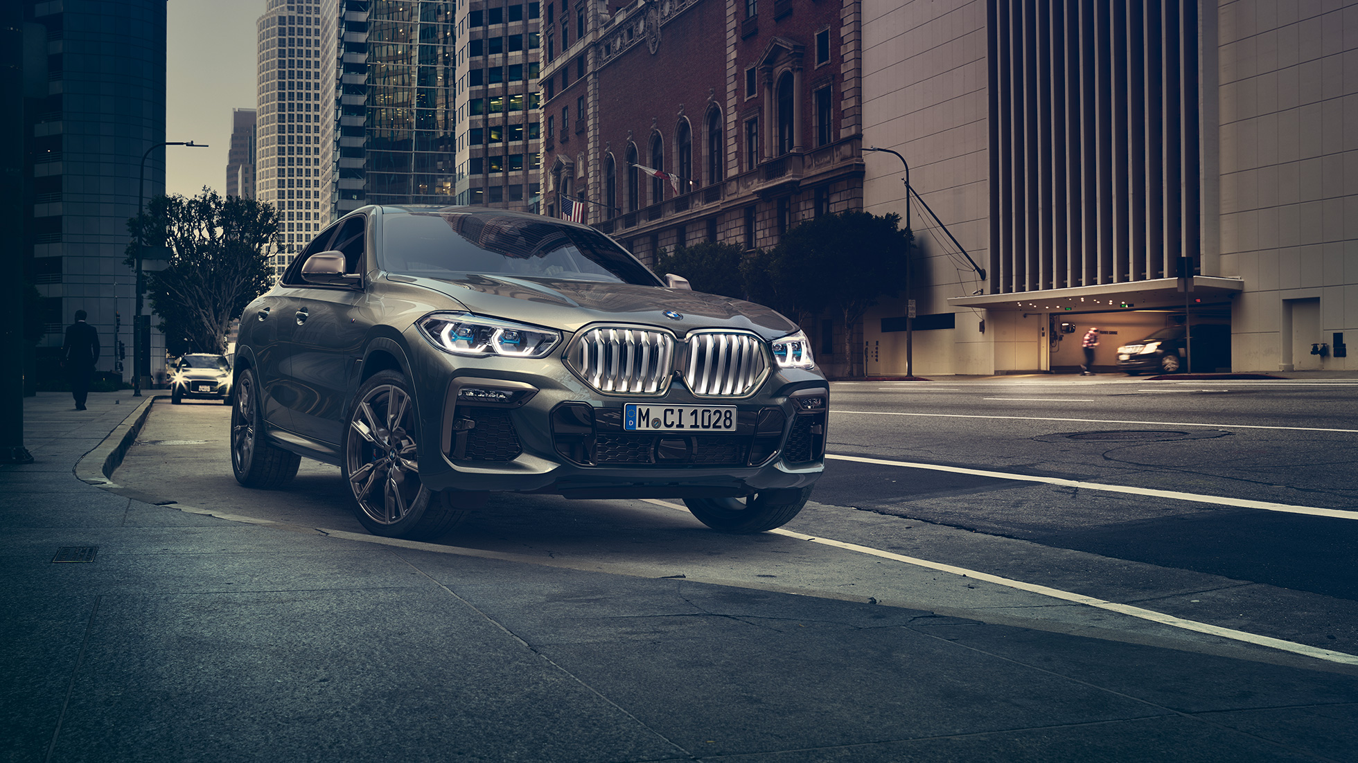Stacionarni BMW X6 M50i BMW X6 M50i u tročetvrtinskoj perspektivi prednjeg kraja ispred urbane pozadine