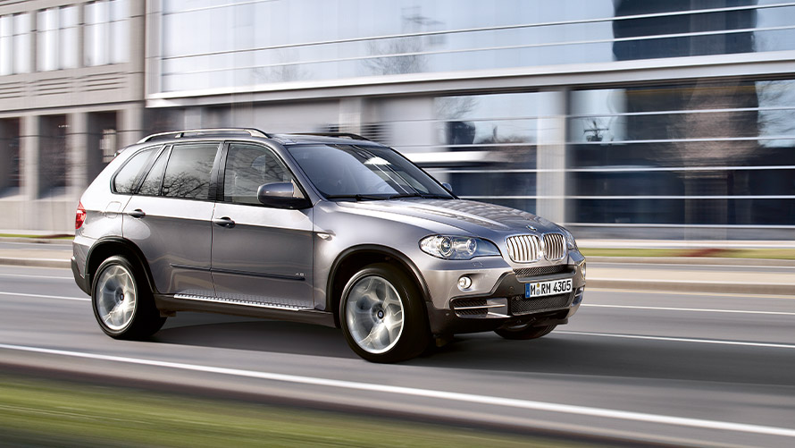 Bočni prikaz BMW-a X5 E70 druge generacije u vožnji ulicom BMW serije X; Bočni prikaz BMW-a X5 E70 druge generacije u vožnji ulicom
