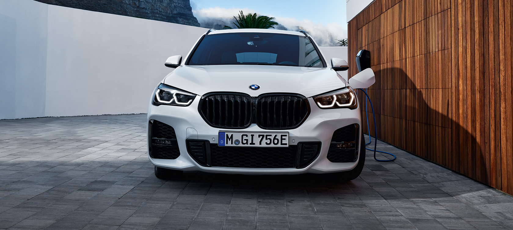 Tročetvrtinski bočni prikaz plug-in hibrida BMW-a X1 xDrive25e F48 na napajanju s modelom Tročetvrtinski bočni prikaz plug-in hibrida BMW-a X1 xDrive25e F48 na napajanju s modelom