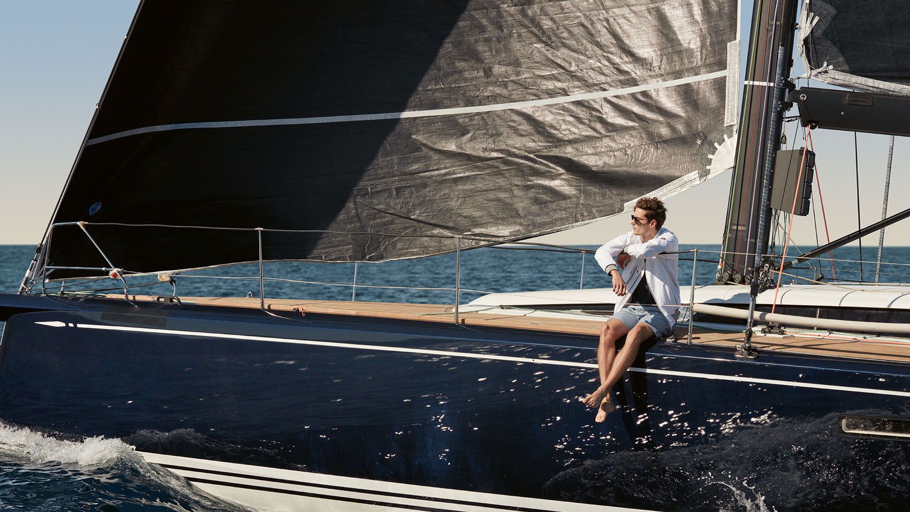 Muškarac je prikazan kako sjedi na jahti i nosi BMW Yachtsport mušku jaknu iz BMW Yachtsport kolekcije. Muškarac je prikazan kako sjedi na jahti i nosi BMW Yachtsport mušku jaknu iz BMW Yachtsport kolekcije.