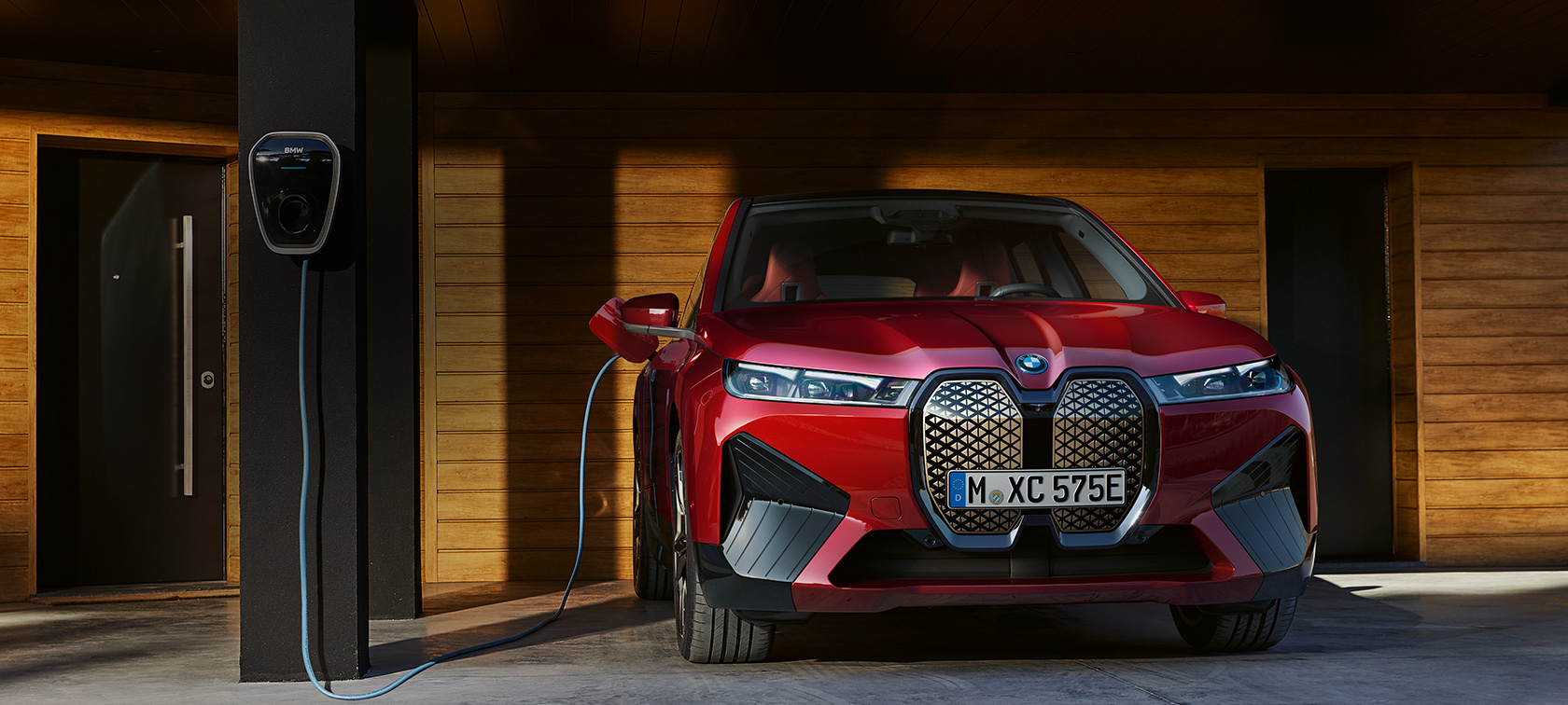BMW iX kod kuće sa wallboxom u garaži u pogledu sprijeda BMW iX kod kuće sa wallboxom u garaži s drvenim oblogama s prednje strane