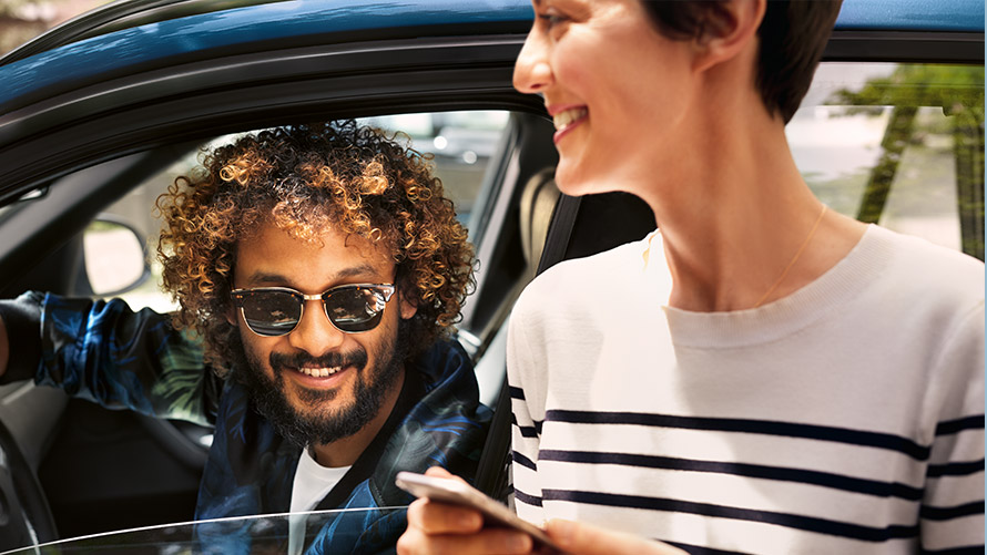 BMW Connected Čovjek u BMW-u i žena izvan BMW-a koriste BMW Connected na pametnom telefonu