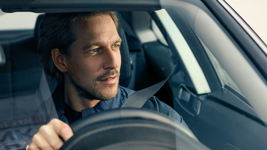 Muškarac vozi BMW Muškarac koji vozi BMW gleda kroz vjetrobransko staklo